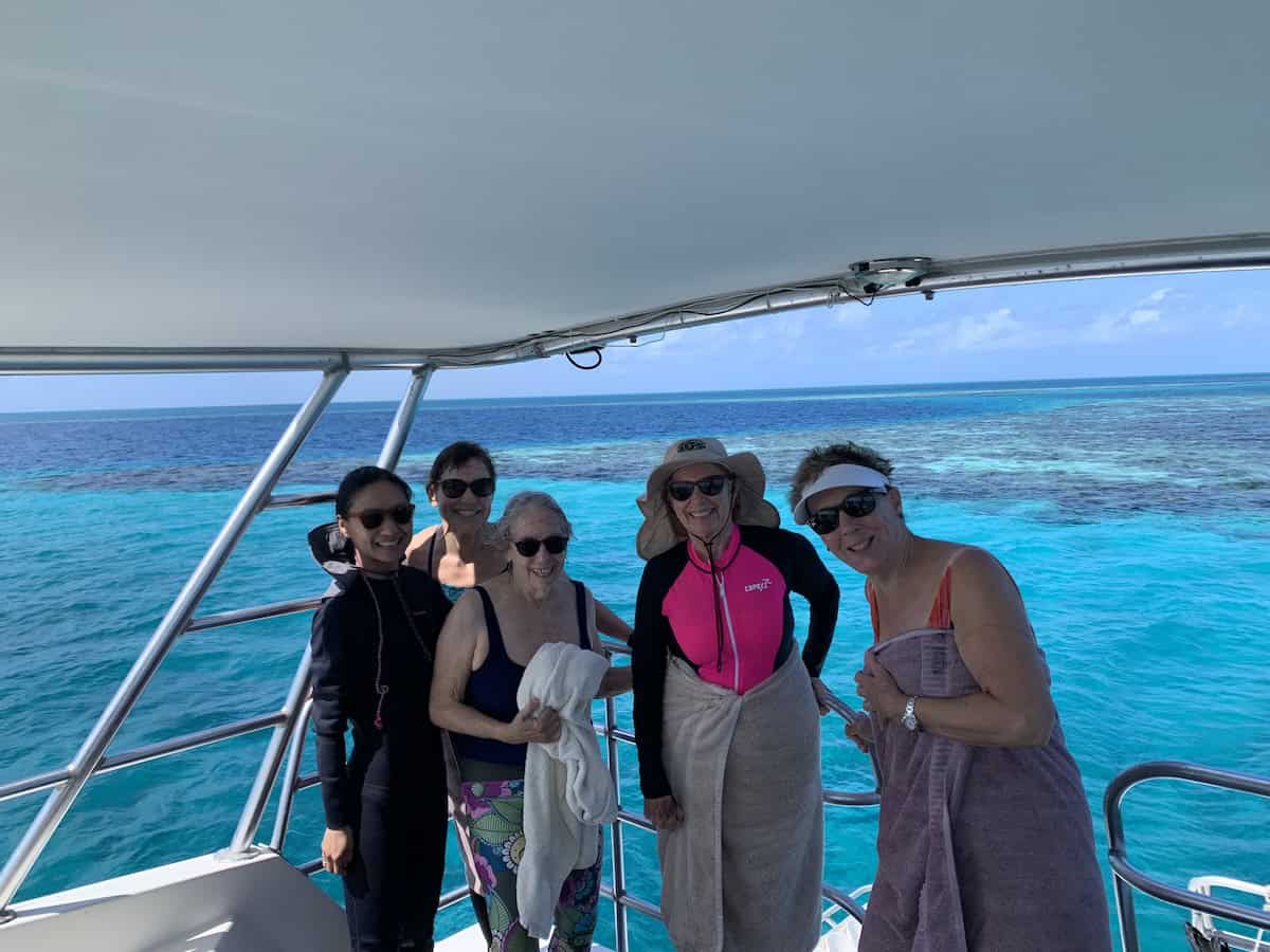 All-women travelers pose together on a boat after snorkeling in the Belize Great Blue Hole during an Oceanic Society expedition.