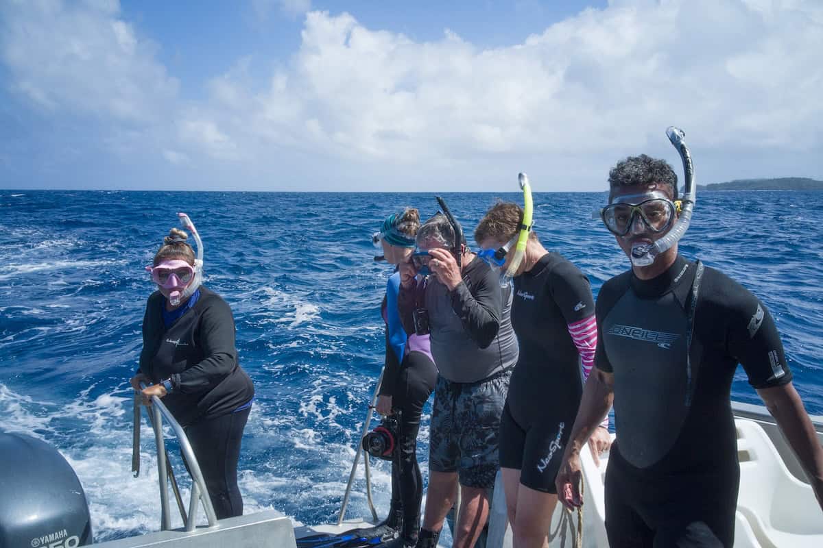 Snorkelers standing at stern of boat in open ocean water